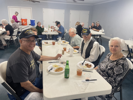  Frank Espinosa Jr., (left), Jutta Hedges (front right) and Jim Hedges (back right) sit at a table together for the  National Vietnam War Veterans Day fish fry March 29. 