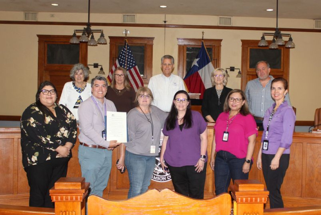 The Williamson County Commissioners, back row, along with Michael Aguirre, left, and case workers from Adult Protective Services, pose with the proclamation making June Elder Abuse Awareness Month during the June 18 Commissioners Court meeting. Photo courtesy of Williamson County. 