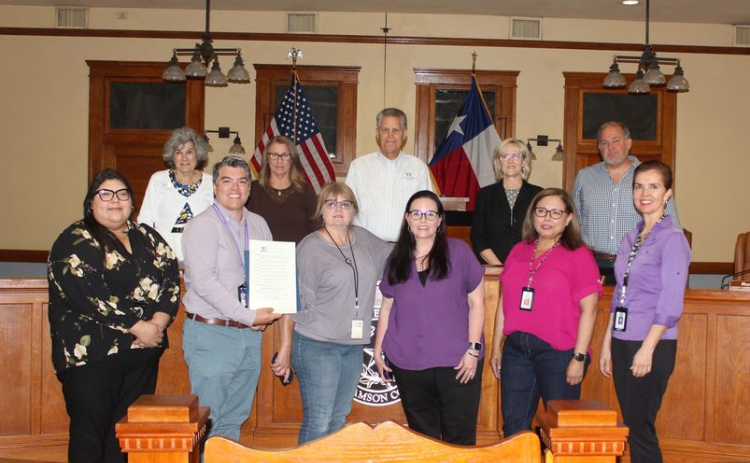 The Williamson County Commissioners, back row, along with Michael Aguirre, left, and case workers from Adult Protective Services, pose with the proclamation making June Elder Abuse Awareness Month during the June 18 Commissioners Court meeting. Photo courtesy of Williamson County. 